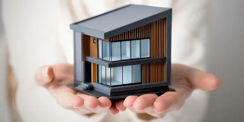 Miniatyrhus i händer som illustrerar proptech och smart fastighetsteknik.
