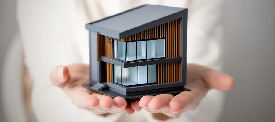 Miniatyrhus i händer som illustrerar proptech och smart fastighetsteknik.